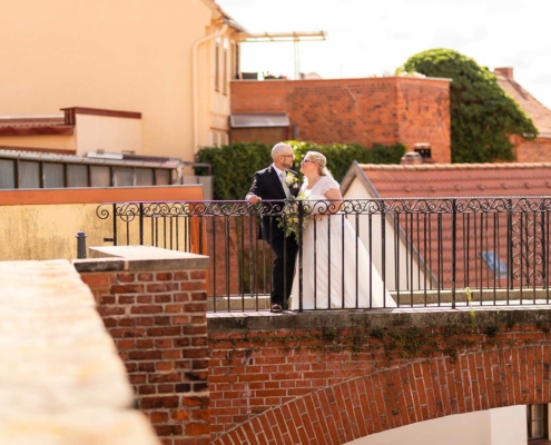 Anna und Stefan stehen auf einer Brücke in Tangermünde, schauen sich verliebt an, Anna hält den Brautstrauß, als Titelbild für die Hochzeitsreportage.