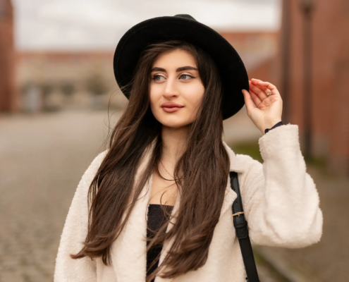 Portrait einer jungen Frau mit schwarzem Hut und langem Haar beim Fotoshooting in Stendal – Winterlook mit hellem Mantel