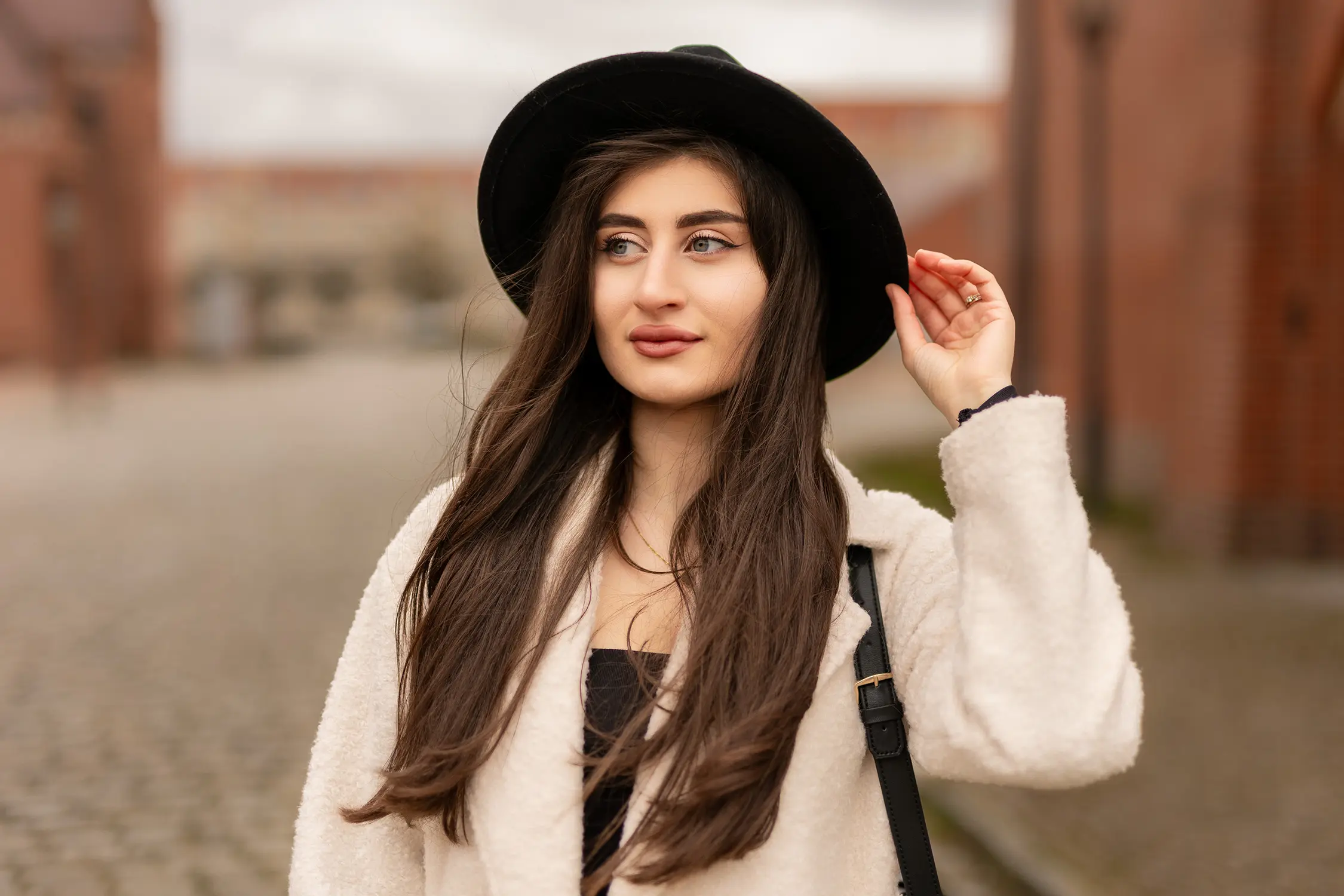Portrait einer jungen Frau mit schwarzem Hut und langem Haar beim Fotoshooting in Stendal – Winterlook mit hellem Mantel